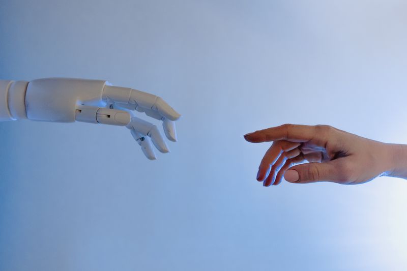 mano humana y de robot casi tocándose